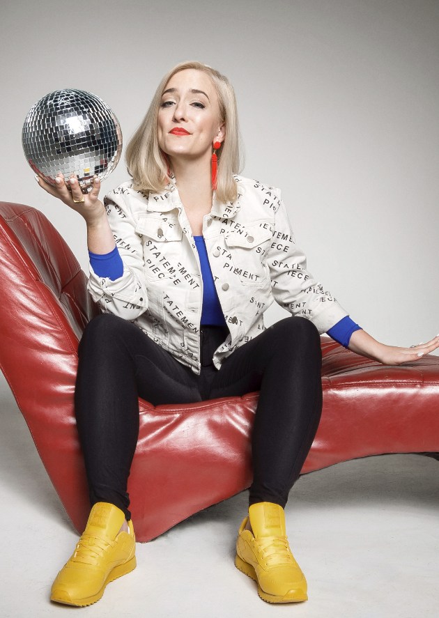 A woman on a red leather coach holds a disco mirrorball