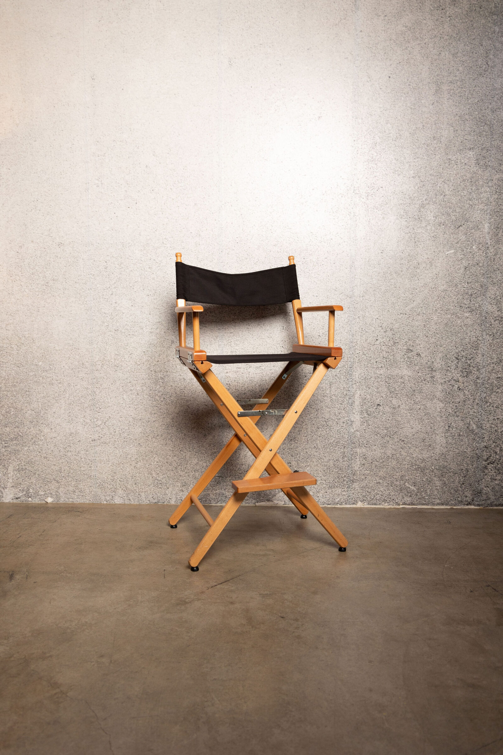 Director's chair in against a cement wall.