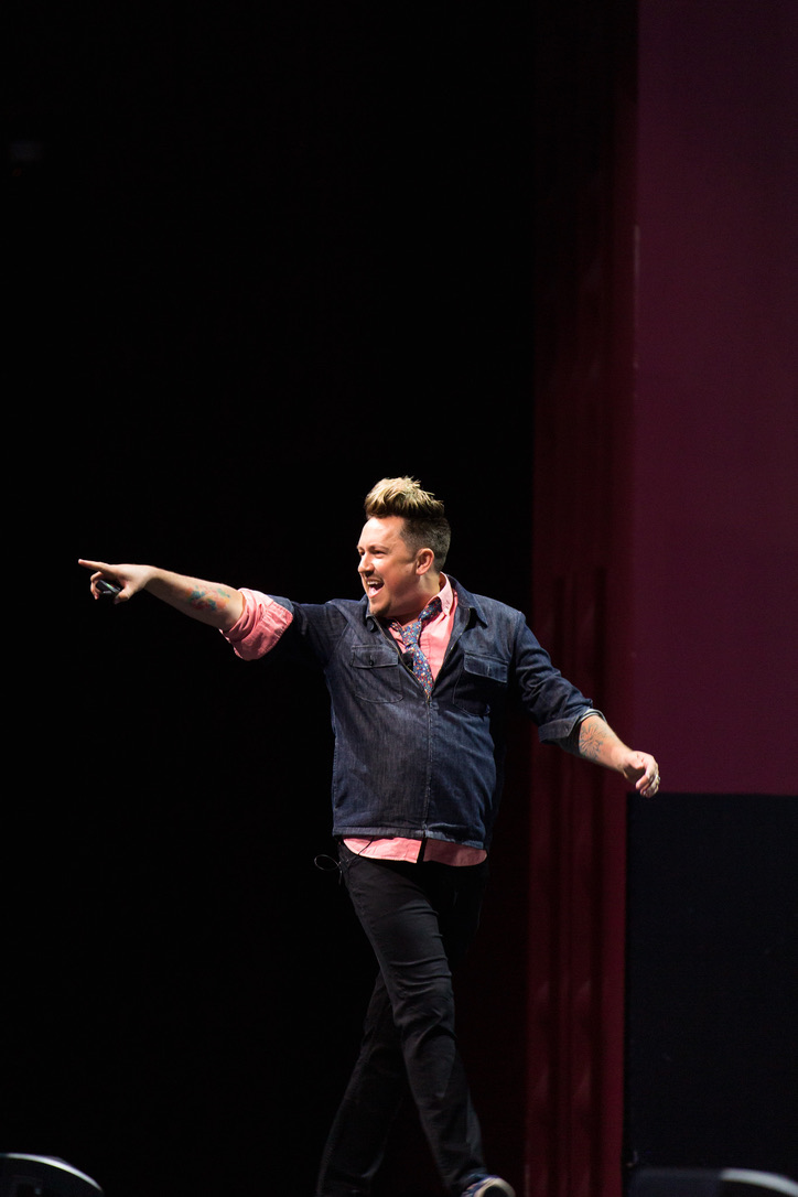 A keynote speaker walking on stage and pointing to an audience